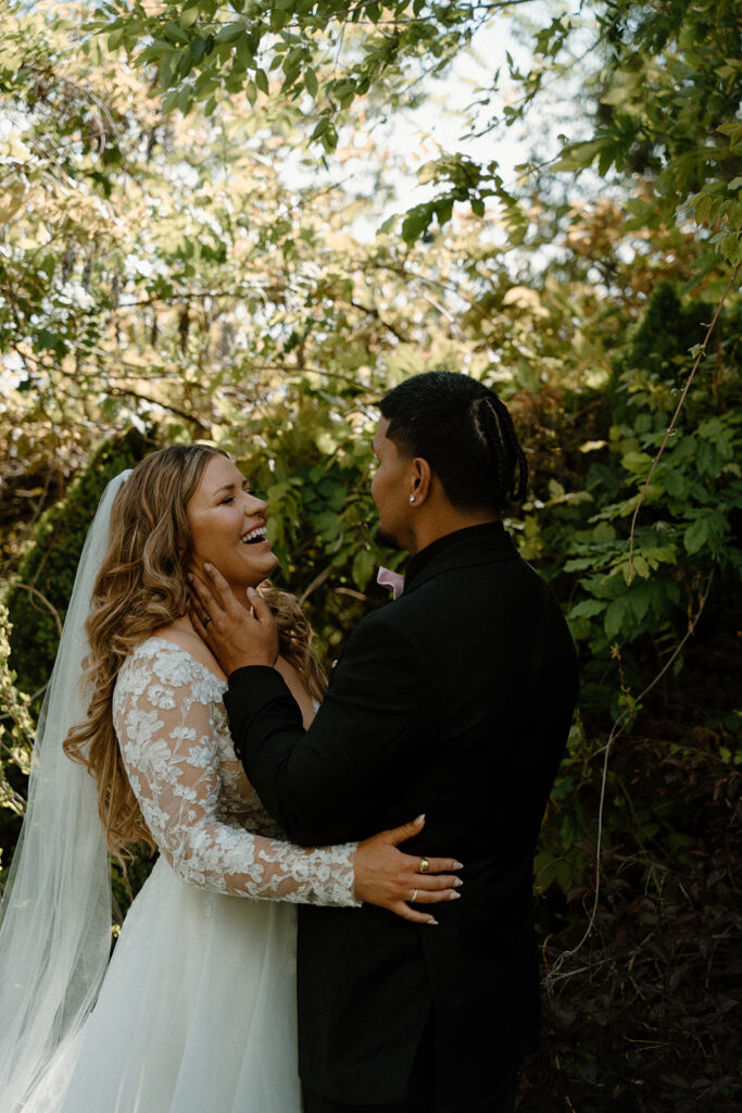 Bride and groom in a lush green garden laughing