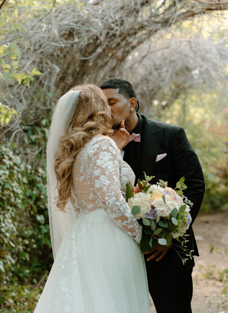 Soft romantic portrait of bride and groom under wisteria in a reno wedding